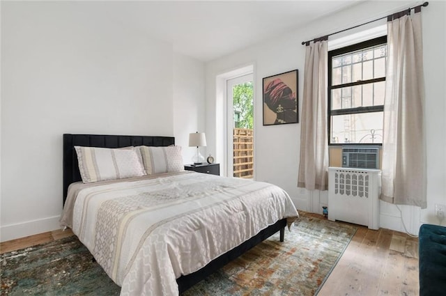 bedroom featuring radiator heating unit, cooling unit, and wood-type flooring