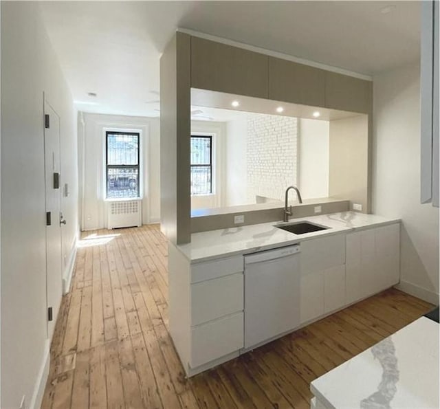 kitchen featuring white cabinetry, dishwasher, sink, radiator heating unit, and light hardwood / wood-style flooring