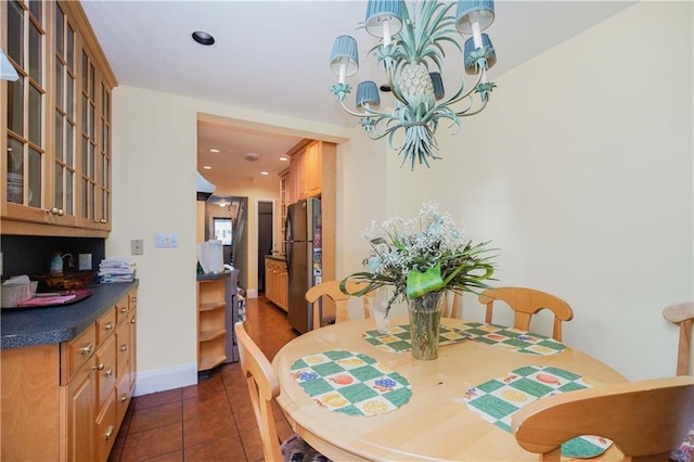 dining space featuring dark tile patterned flooring and an inviting chandelier