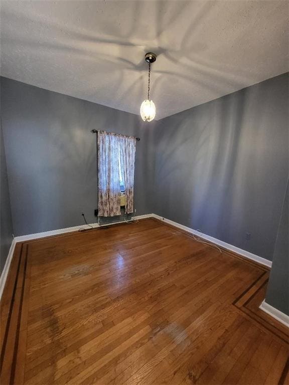 empty room with hardwood / wood-style floors and a textured ceiling