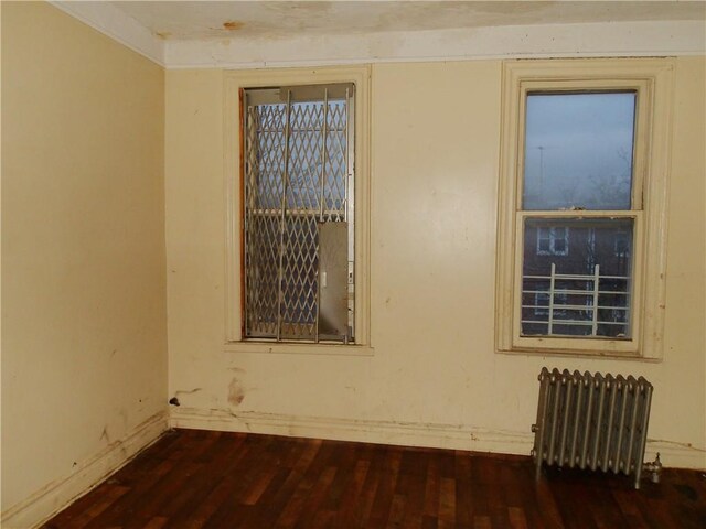 unfurnished room with dark hardwood / wood-style flooring and radiator