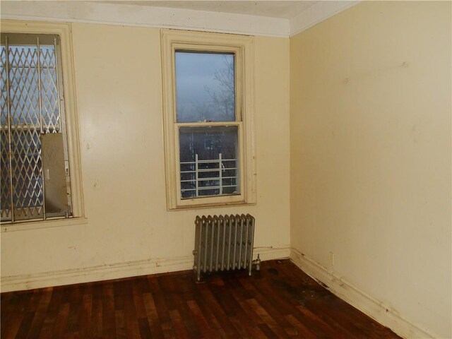 unfurnished room with radiator heating unit and dark hardwood / wood-style floors