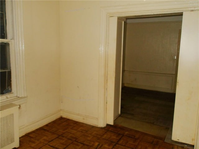 empty room featuring radiator and dark parquet floors