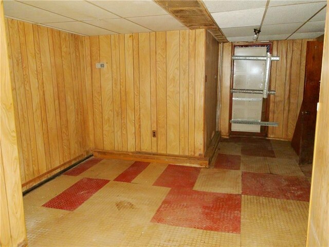 empty room with a drop ceiling and wooden walls