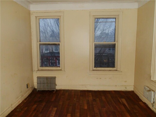 spare room featuring radiator heating unit and dark hardwood / wood-style flooring