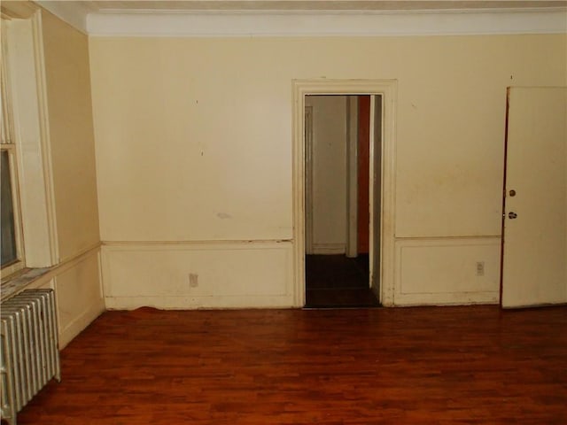 spare room featuring dark wood-type flooring and radiator heating unit