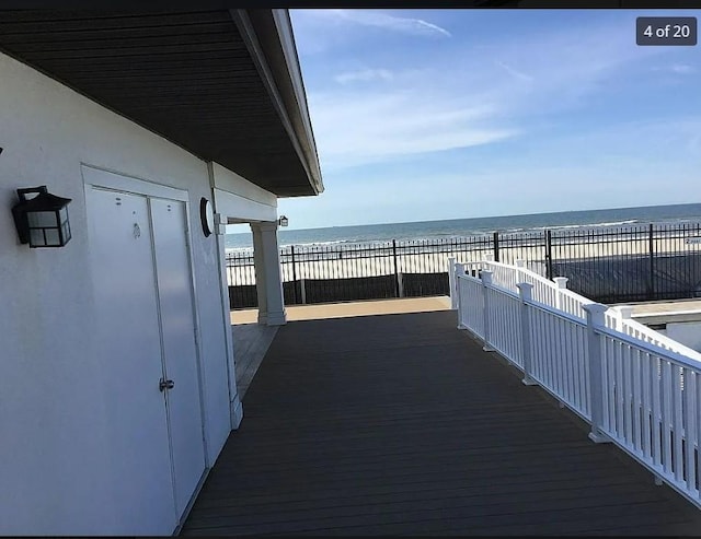 wooden deck featuring a water view and a view of the beach