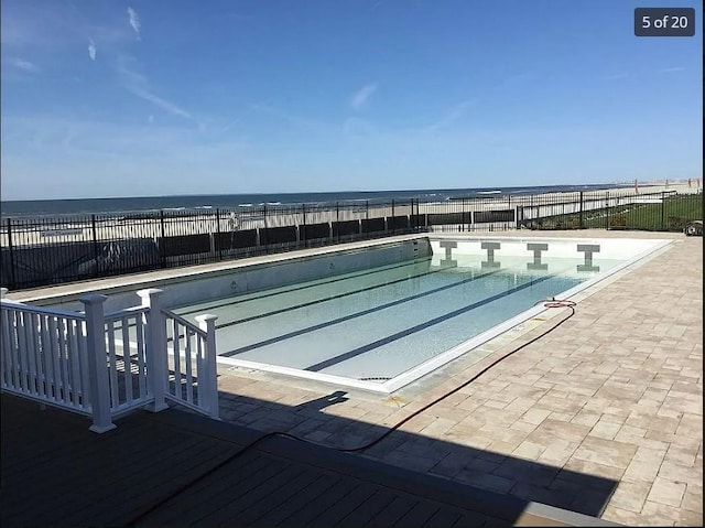 view of pool with a water view and a patio