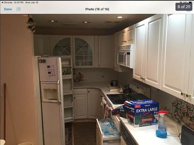 kitchen with white appliances, white cabinets, glass insert cabinets, light countertops, and recessed lighting