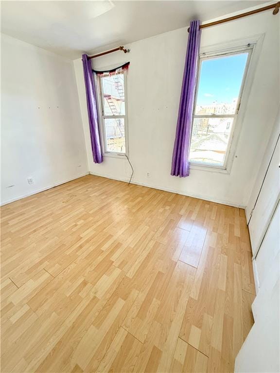 empty room with light wood-type flooring and baseboards