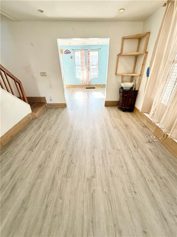 unfurnished room featuring wood finished floors, baseboards, and stairs