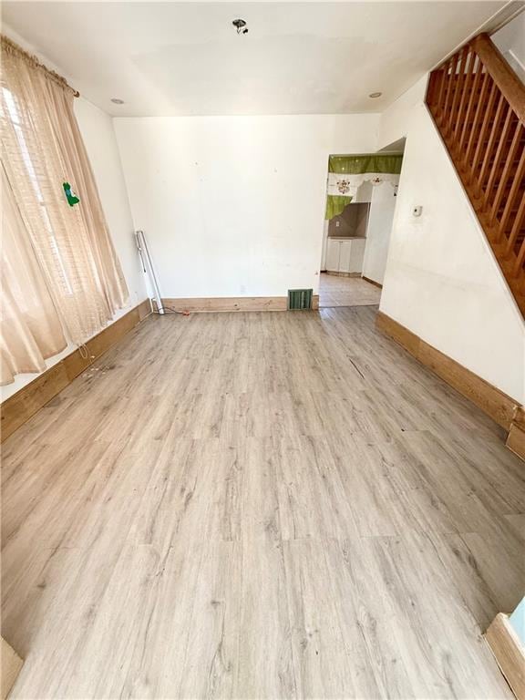 unfurnished living room featuring wood finished floors and baseboards