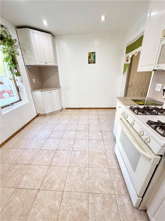 kitchen featuring white cabinetry, white gas range, and light tile patterned flooring