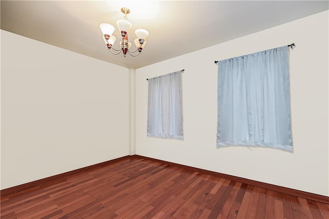 empty room featuring dark hardwood / wood-style floors and a chandelier