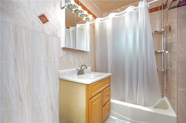 bathroom featuring vanity, shower / bathtub combination with curtain, and tile walls