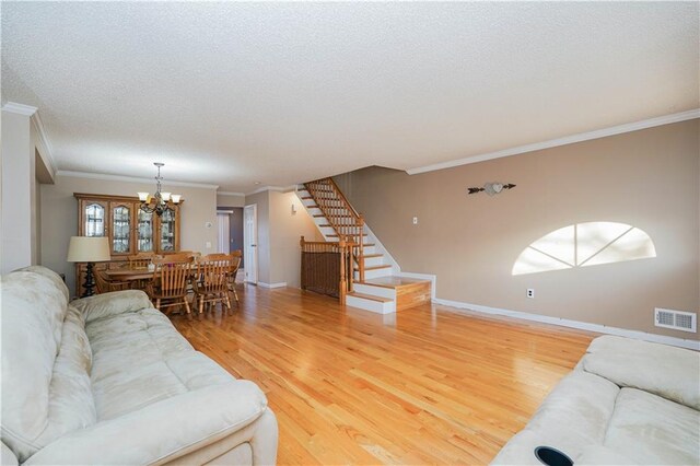 living room featuring a textured ceiling, hardwood / wood-style flooring, an inviting chandelier, and crown molding