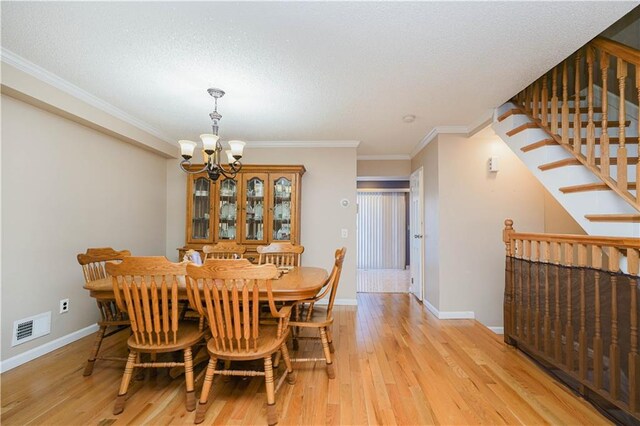 dining area featuring a textured ceiling, light hardwood / wood-style floors, an inviting chandelier, and ornamental molding