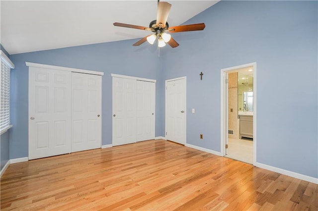 unfurnished bedroom with multiple closets, ceiling fan, high vaulted ceiling, ensuite bathroom, and light hardwood / wood-style floors