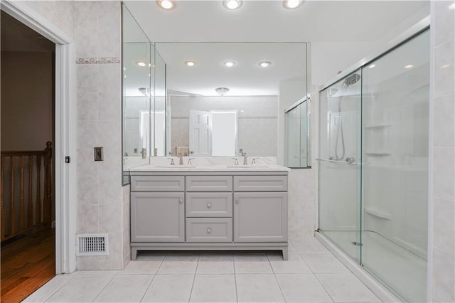 bathroom with tile patterned flooring, vanity, tile walls, and walk in shower