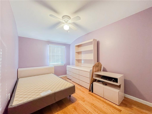 bedroom with ceiling fan, light hardwood / wood-style floors, and vaulted ceiling