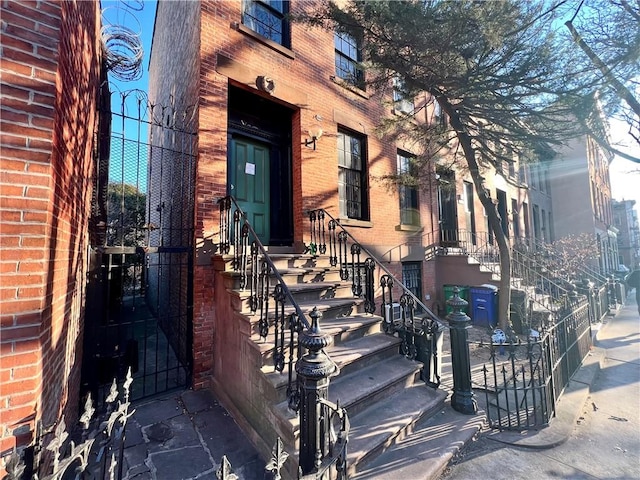 doorway to property with brick siding and a gate