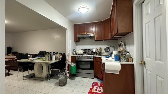 129 Bay 40th St, Brooklyn, NY 11214 - kitchen with gas range, under cabinet range hood, light countertops, decorative backsplash, and light tile patterned floors