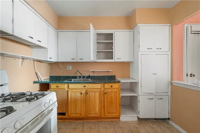 kitchen featuring white range with gas stovetop, a sink, white cabinetry, baseboards, and open shelves