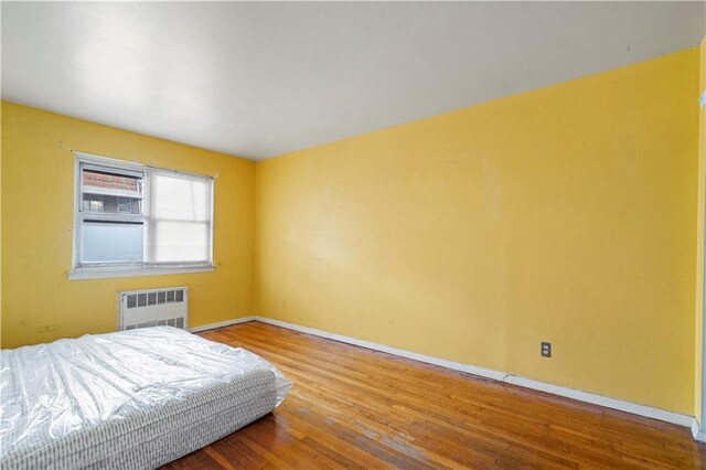 bedroom featuring radiator and hardwood / wood-style floors