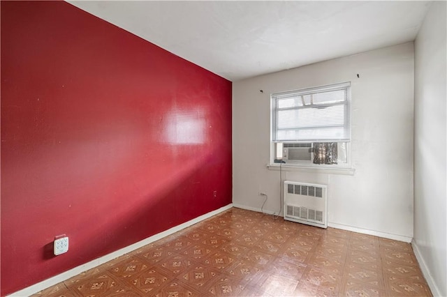 empty room featuring radiator, light floors, baseboards, and cooling unit