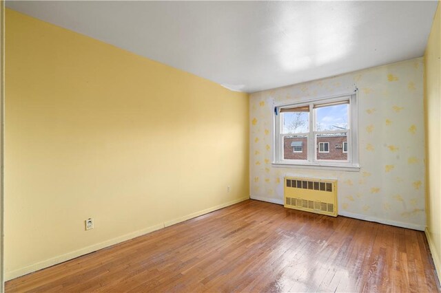 spare room featuring wood-type flooring and radiator