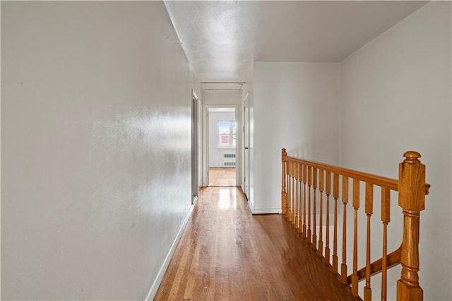 corridor featuring radiator, attic access, an upstairs landing, wood finished floors, and baseboards