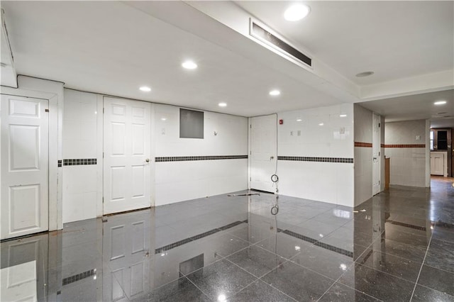 spare room featuring tile walls, granite finish floor, visible vents, and recessed lighting