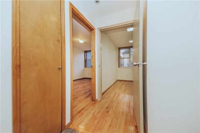 corridor featuring baseboards and light wood finished floors