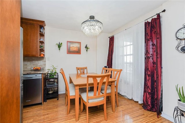 dining area featuring a chandelier, light wood-style flooring, and baseboards