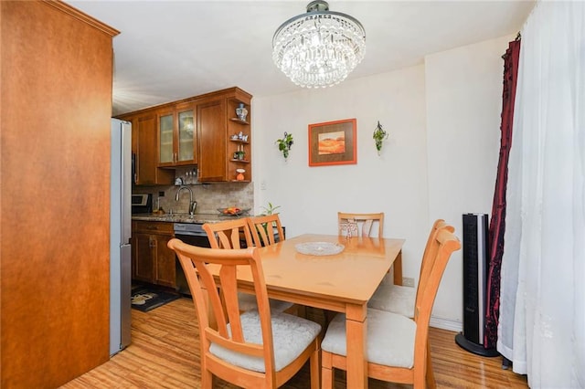 dining area with light wood-style floors, baseboards, and an inviting chandelier