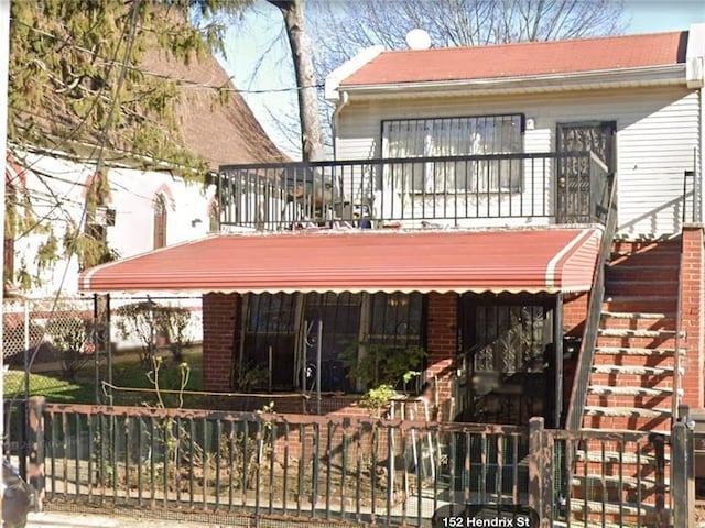 rear view of house with brick siding and fence