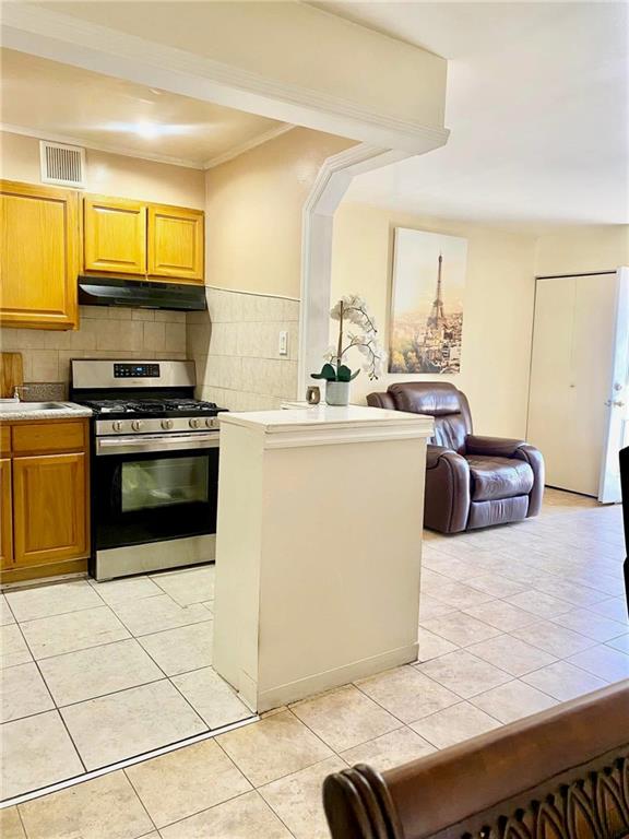 153 Hendrix St, Brooklyn, NY 11207 - kitchen with visible vents, gas range, light tile patterned floors, and under cabinet range hood