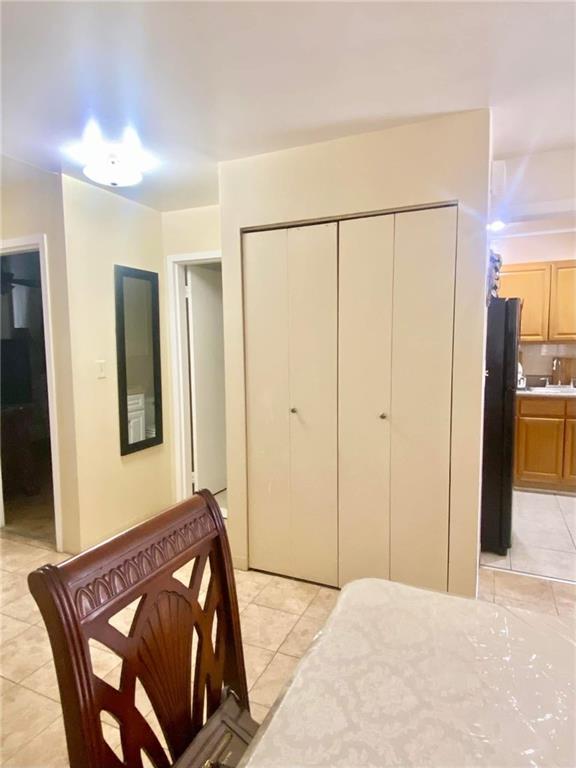 153 Hendrix St, Brooklyn, NY 11207 - bedroom with light tile patterned floors, a closet, freestanding refrigerator, and connected bathroom