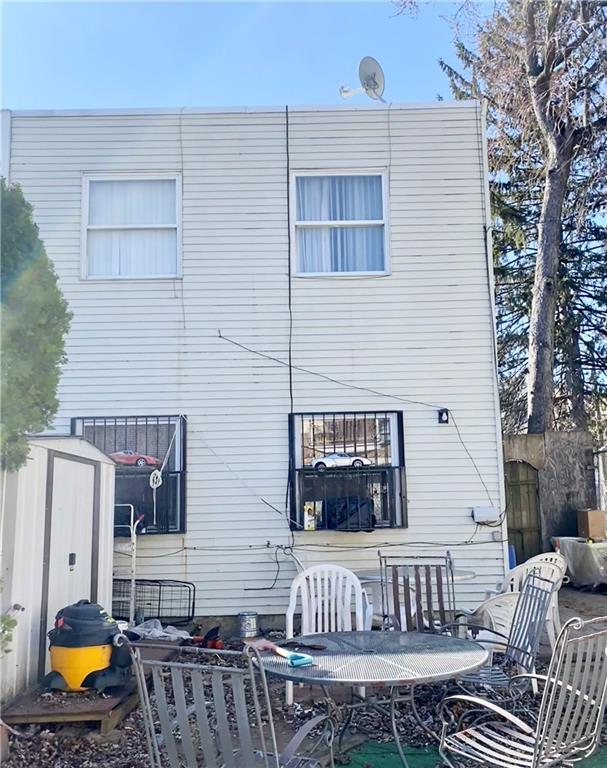 153 Hendrix St, Brooklyn, NY 11207 - back of property with a storage shed, outdoor dining space, fence, and an outbuilding