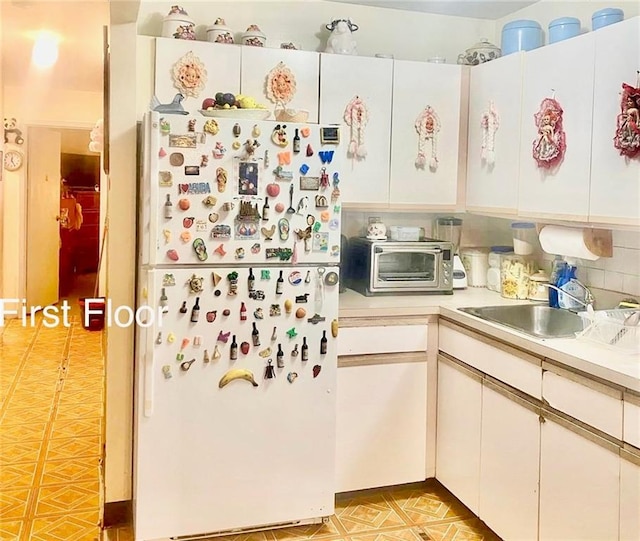 153 Hendrix St, Brooklyn, NY 11207 - kitchen featuring a sink, light countertops, freestanding refrigerator, white cabinetry, and a toaster