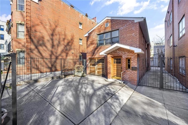 back of house with a fenced front yard, a gate, and brick siding