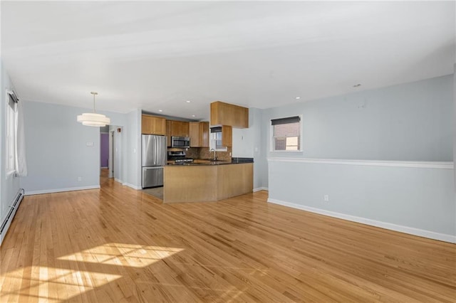 kitchen featuring appliances with stainless steel finishes, sink, backsplash, hanging light fixtures, and light wood-type flooring