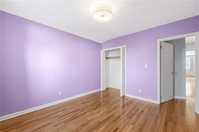 unfurnished bedroom featuring light wood-style flooring, baseboards, and a closet