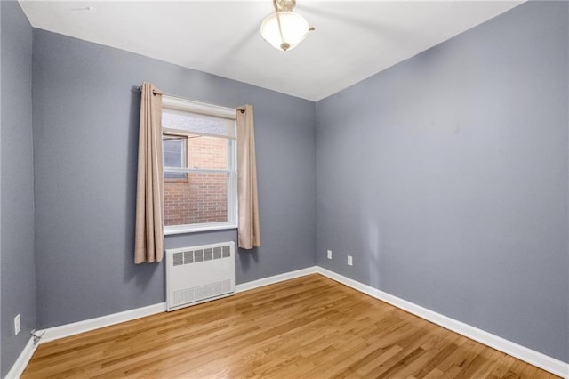 empty room with radiator, baseboards, and wood finished floors