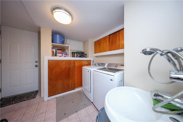 clothes washing area with sink, light tile patterned flooring, cabinets, and independent washer and dryer