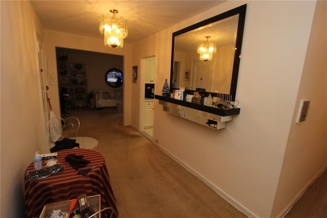 corridor with an inviting chandelier, carpet floors, and baseboards