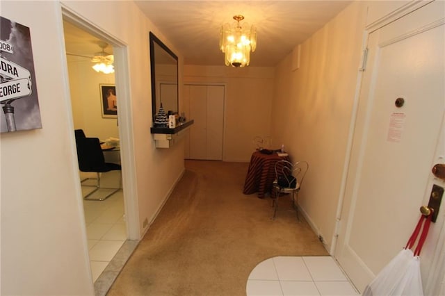 hall with tile patterned floors, an inviting chandelier, and carpet floors