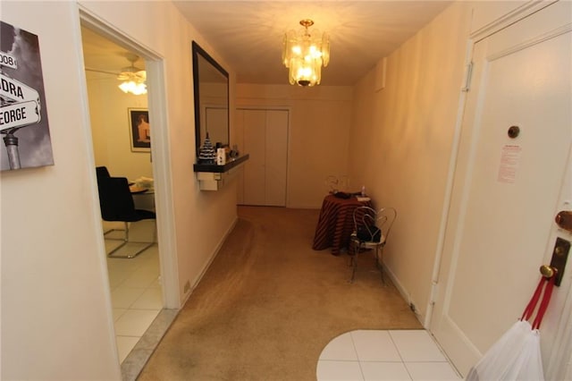 corridor featuring an inviting chandelier, tile patterned flooring, and carpet