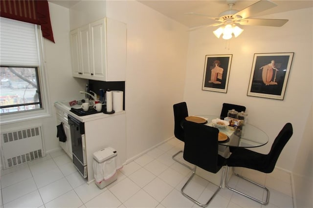 dining space with light tile patterned floors, baseboards, radiator, and a ceiling fan