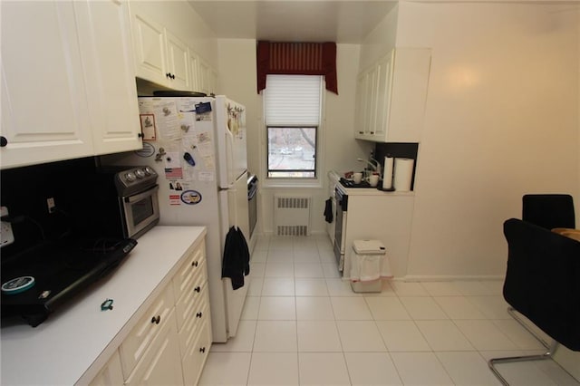 kitchen featuring freestanding refrigerator, light tile patterned floors, light countertops, radiator, and white cabinetry